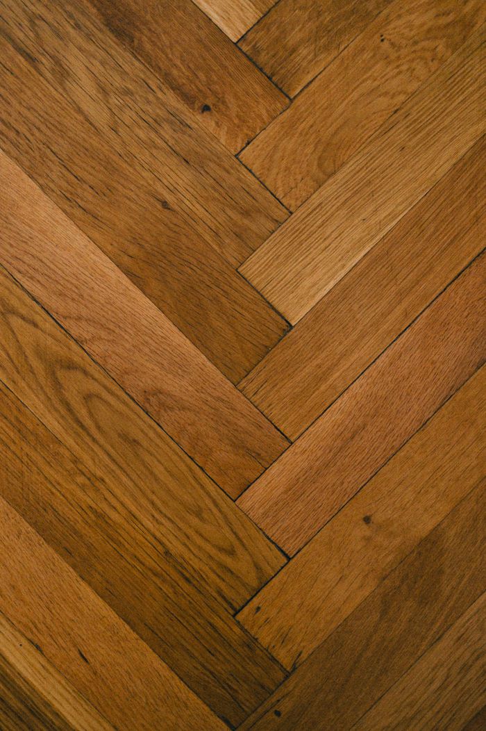 Services Close-up of wooden parquet flooring with a herringbone pattern, showcasing rich brown tones.